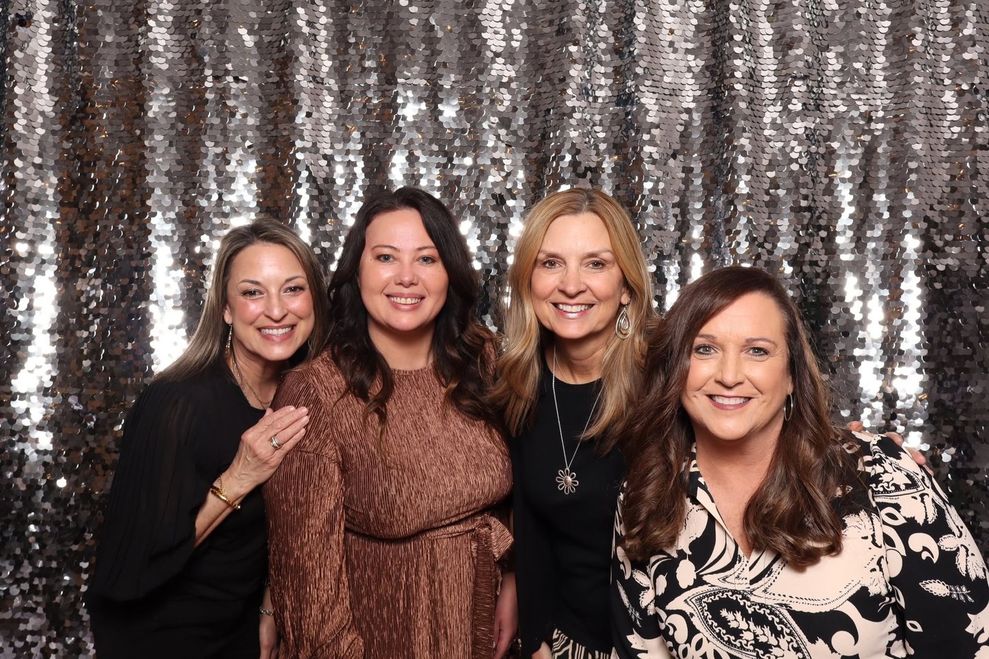 A group of women posing in front of a sequined backdrop